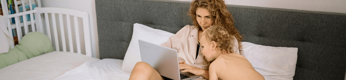 Woman on computer with kid looking on
