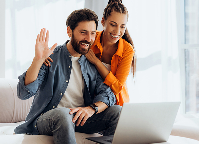 Couple using laptop and smiling.